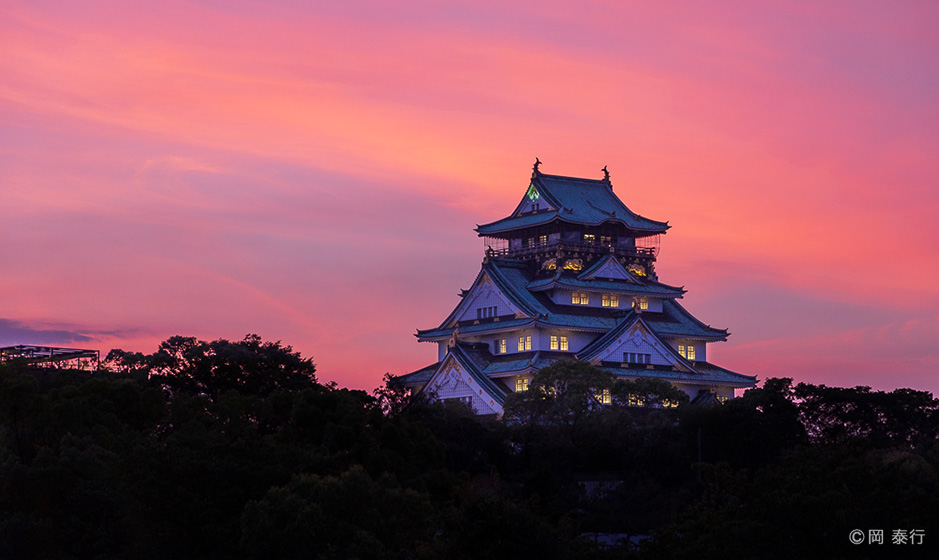 写真1.夕焼けに染まる大阪城天守閣。日暮れとともにライトアップが始まる